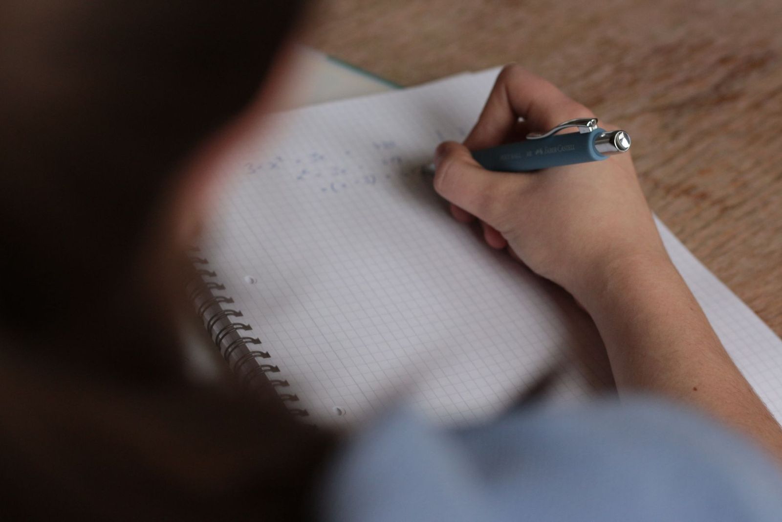 Schüler schreibt mathematische Notizen in ein Heft